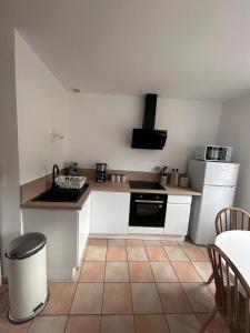 Petite maison au pied du château في Salignac Eyvigues: مطبخ مع أجهزة بيضاء وأرضية من البلاط +7 صور