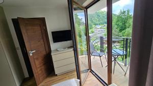 a room with a balcony with a television and a door at Willa Zacisze Szczawnica 15 m2 in Szczawnica