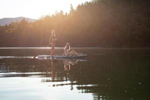 two girls are standing on a paddle board on a lake at Hotel Girlanerhof in Appiano sulla Strada del Vino