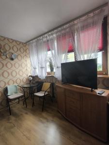a living room with a flat screen tv and windows at Mieszkanie Jelenia in Jelenia Góra