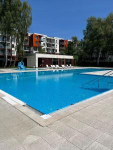 a large blue swimming pool with chairs and a building at Apartament Polanki E207 in Kołobrzeg