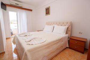 a bedroom with a large bed with white sheets and a window at Villa Abiori 2 in Ksamil