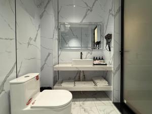 un bagno bianco con lavandino e WC di 合悦精品商务酒店 a Roga