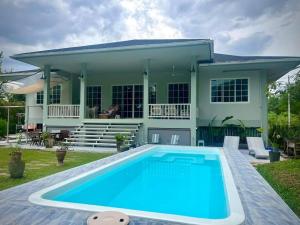 a house with a swimming pool in front of a house at Brook Villa Khaoyai in Pak Chong