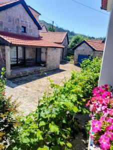 un jardin avec des fleurs roses et une maison en pierre dans l'établissement Casas do Arrabalde, à Amarante