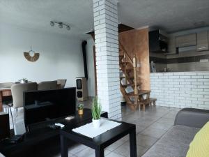 a living room with a couch and a tv and a table at Panoráma Pelsó Apartman in Ábrahámhegy