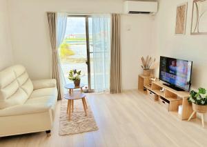 a living room with a couch and a television at ZZOKIAI紫葉 30-second walk to the seaside! You can see the sea from every floor! 4LDK maximun 10 people! in Sunja
