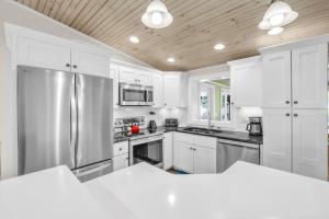 eine Küche mit weißen Schränken und einem Edelstahlkühlschrank in der Unterkunft Ebb Tide Home in Holmes Beach