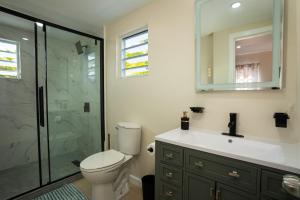 a bathroom with a toilet and a glass shower at Xoop Homes - Ixora #1 in Saint Johnʼs +29 photos