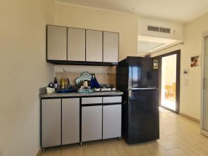 Una cocina con refrigerador negro y gabinetes blancos. en AlDau Heights Modern Studio with Terrace, Mountain & City View, en Hurghada