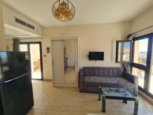 Una sala de estar con un sofá y un televisor. en AlDau Heights Modern Studio with Terrace, Mountain & City View, en Hurghada