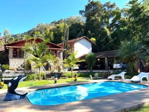 a swimming pool with a dolphin statue in front of a house at Pousada Cascata dos Amores in Teresópolis