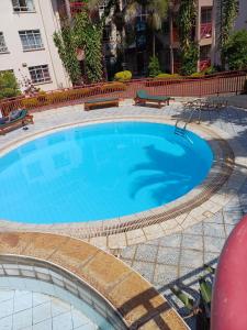 a large blue swimming pool with benches around it at La Pace One Bedroom Home, Rhapta Road Westlands Nairobi in Nairobi