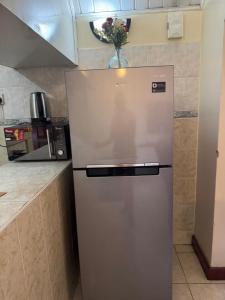 a refrigerator in a kitchen with a vase of flowers at La Pace One Bedroom Home, Rhapta Road Westlands Nairobi in Nairobi