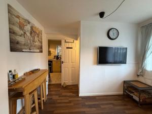 a living room with a table and a clock on a wall at Grundy House in Uxbridge +37 photos