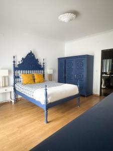 a bedroom with a blue bed with yellow pillows at Offshore Rustic House in Peniche