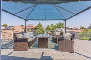 a patio with two chairs and a table under a blue umbrella at Comics & Cars - Themed Penthouse in Motor Valley in Modena