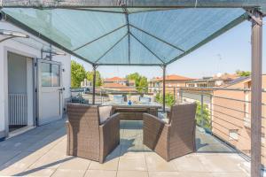 a patio with two chairs and a blue umbrella at Comics & Cars - Themed Penthouse in Motor Valley in Modena