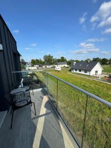 a balcony with a table and chairs and a field at Apartament Kasztanówka w Rydzynie in Kłoda