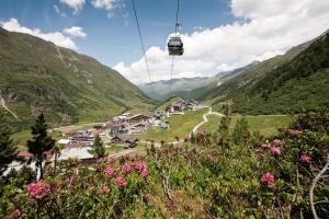 a gondola flying over a village in the mountains at 4 Sterne Superior Mühle Resort 1900 - Adults only in Obergurgl