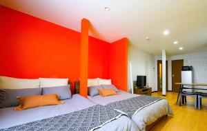 a bedroom with a large bed with an orange wall at Rambler 202 in Sapporo
