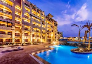 un hotel con piscina frente a un edificio en AlDau Heights Modern Studio with Terrace, Mountain & City View, en Hurghada