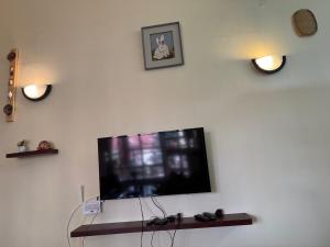 a flat screen tv on a white wall with two clocks at La Pace One Bedroom Home, Rhapta Road Westlands Nairobi in Nairobi