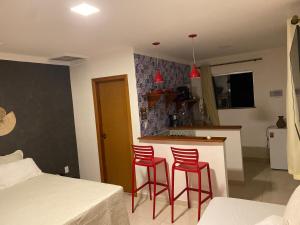 a kitchen with two red bar stools in a room at Loft Confortável in Porto Seguro
