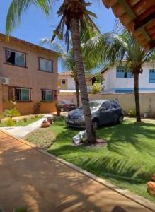 a car parked in front of a house with palm trees at Loft Confortável in Porto Seguro