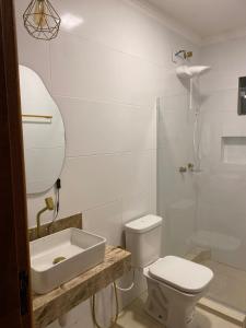a white bathroom with a toilet and a sink at Loft Confortável in Porto Seguro