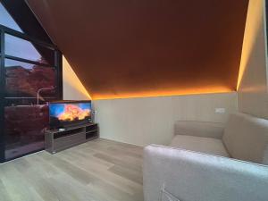 a living room with a couch and a flat screen tv at Noree Jacuzzi Home in Ban Phan Sadet Nai