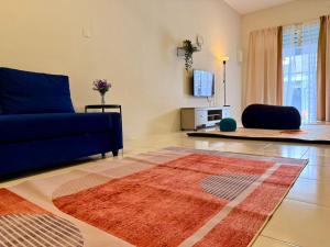 a living room with a blue couch and a rug at 28 Harmoni Homestay, Kamunting in Kamunting +7 photos