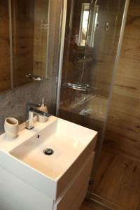 une salle de bain avec un lavabo blanc et une douche dans l'établissement Apartments Cipresa, à Portorož