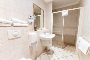 a white bathroom with a sink and a shower at Hotel Arena le Refuge in Corte