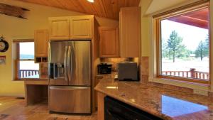eine Küche mit Edelstahlkühlschrank und Fenster in der Unterkunft Lakeside Oasis in Big Bear Lake
