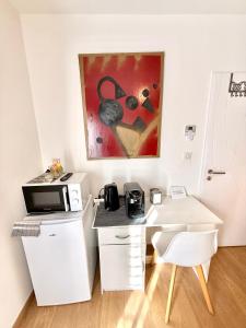 a white desk with a microwave and a painting on the wall at Studio Cosy - CLIM & Parking & WIFI in Aucamville