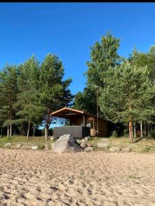 a cabin on the beach with a rock on the sand at Ranna majake, Lake cottage , Peipsi Talu in Rootsiküla