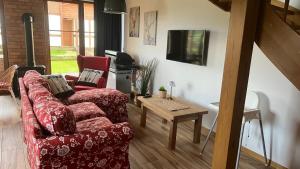 a living room with a red couch and a table at Nowoczesny dom wakacyjny "Sole" nad jeziorem Gwiazdy, Ostoja Bukowo, Borowy Młyn, Kaszuby, region Gochy, z dala od miasta, dookoła lasy in Borowy Młyn