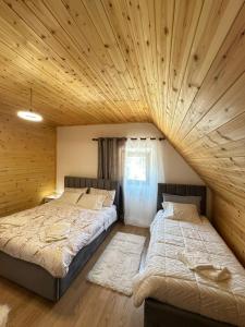 two beds in a room with wooden ceilings at Lodge Martini Theth in Theth +12 photos