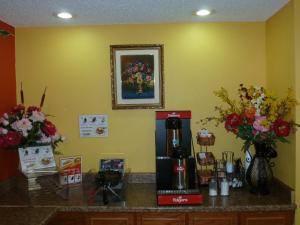 a counter with a coffee maker and vases of flowers at Redwood Inn - White Hall in White Hall