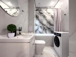 Un baño blanco con lavabo y lavadora. en Raimbek19-45 Residence 1BR nearby metro & drinking water as a gift, en Almaty 10 fotos más