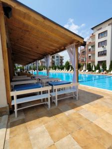 a pavilion with tables and benches next to a pool at Famagusta Antoniya in Aheloy