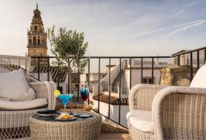 a balcony with wicker chairs and a table with a drink at Balcón de Córdoba in Córdoba