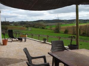 a patio with a table and chairs and a view of a field at Maison Youkie in Saint-Arailles