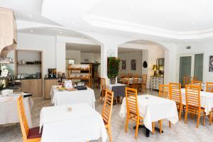 a dining room with white tables and chairs at Hotel Arena le Refuge in Corte