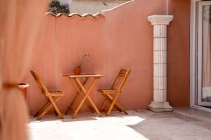 two chairs and a table next to a wall at L'Escale Romaine - Expérience Antique Unique - Centre Historique Orange in Orange +9 photos