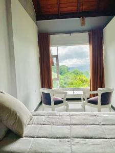 a bedroom with a bed and two chairs and a window at Heavenly Horizon Villa in Kandy
