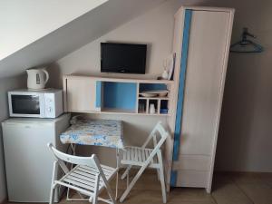a room with a desk with a tv and a table and chairs at Pestka in Jastarnia