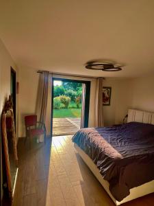 a bedroom with a bed and a sliding glass door at Belle Villa Terra Mare classée 4 étoiles entre océan et bassin in Lège-Cap-Ferret