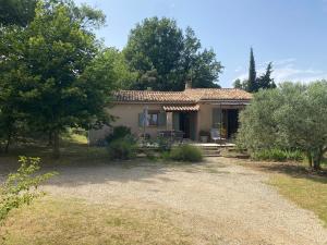 a small house with a gravel driveway and trees at La Manaude in Ménerbes